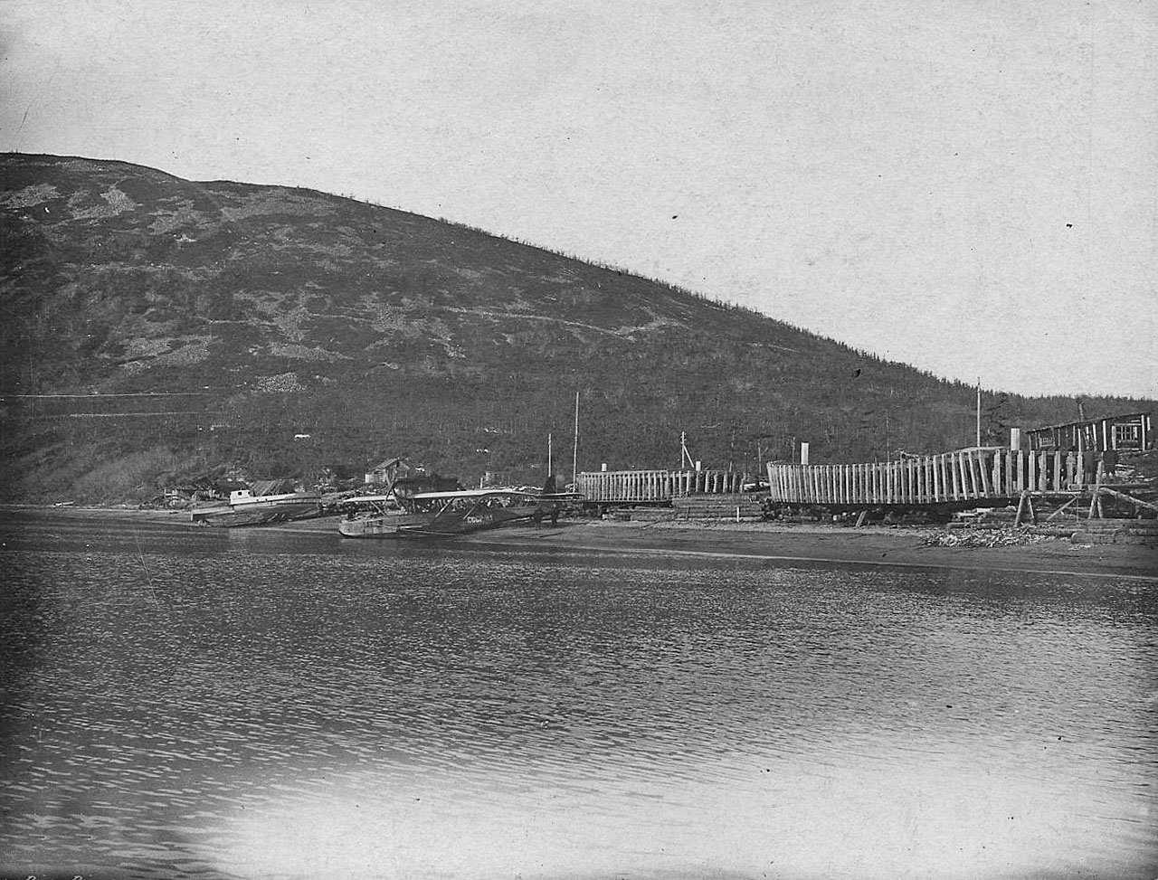 Аэродром в бухте Нагаево. На берегу строящиеся кунгасы и баржи морского типа. У берега - летающая лодка «Dorner-Wal» Н-1. 1933 год