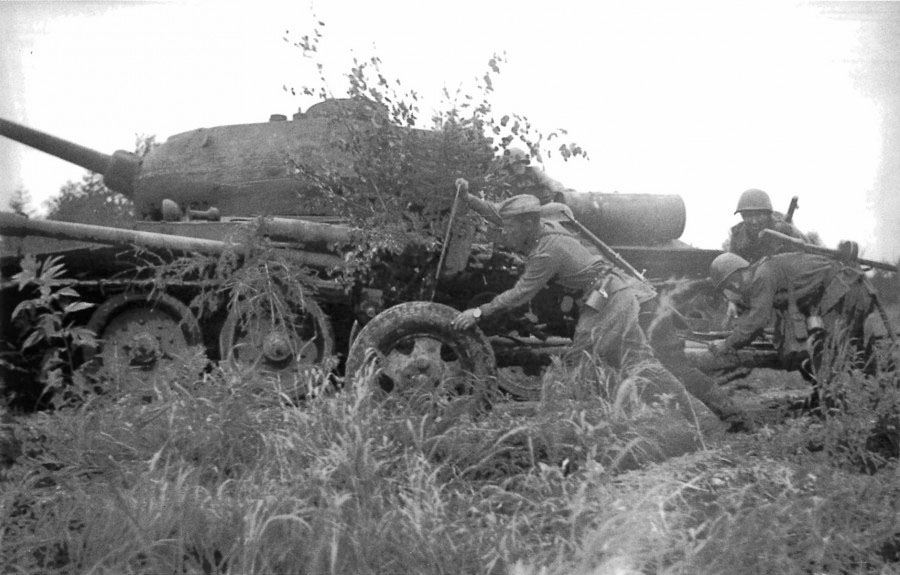 Расчет советской 76-мм пушки ЗиС-3 меняет позицию на Сахалине у танка Т-34-85.